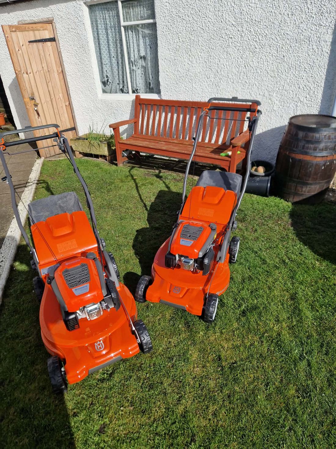Two mowers ready to start on a cut lawn.